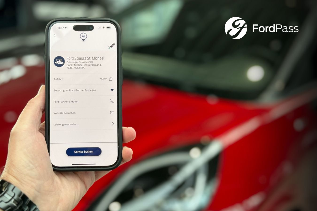 Anzeige der Ford Pass App auf einem Handy im Autohaus Strauss Schauraum vor einem Fahrzeug